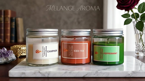 A curated trio of Melange Aroma Freshness candles styled on a wooden tray with fresh mint leaves and a glass of iced tea.